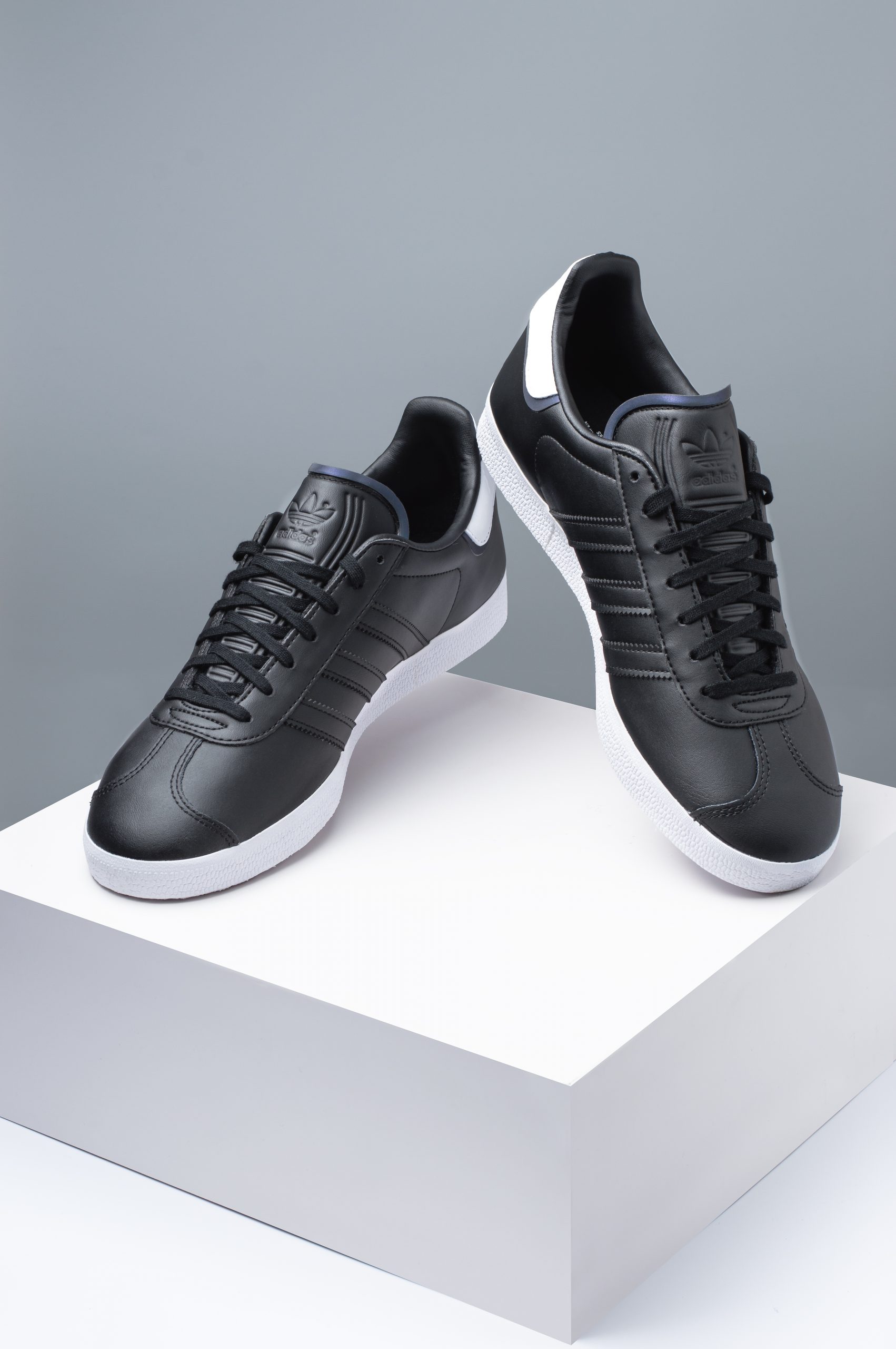 Adidas Gazelle black leather trainers shown as a pair from angled side view