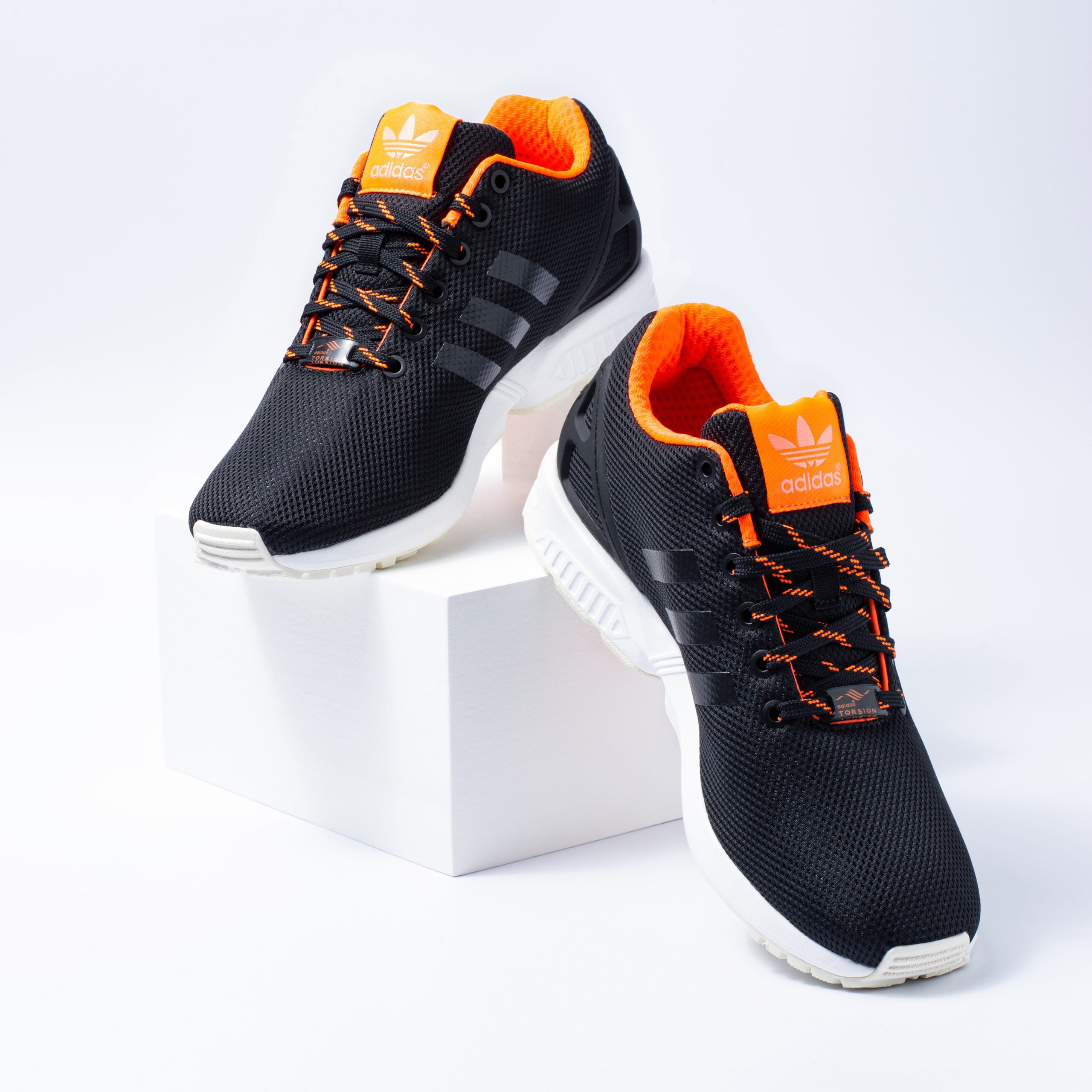 Adidas ZX Flux trainers in navy and orange displayed on white box
