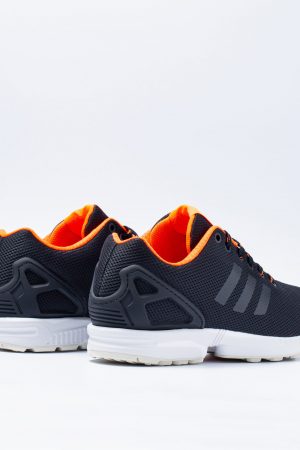 Adidas ZX Flux trainers in navy and orange viewed head-on from behind